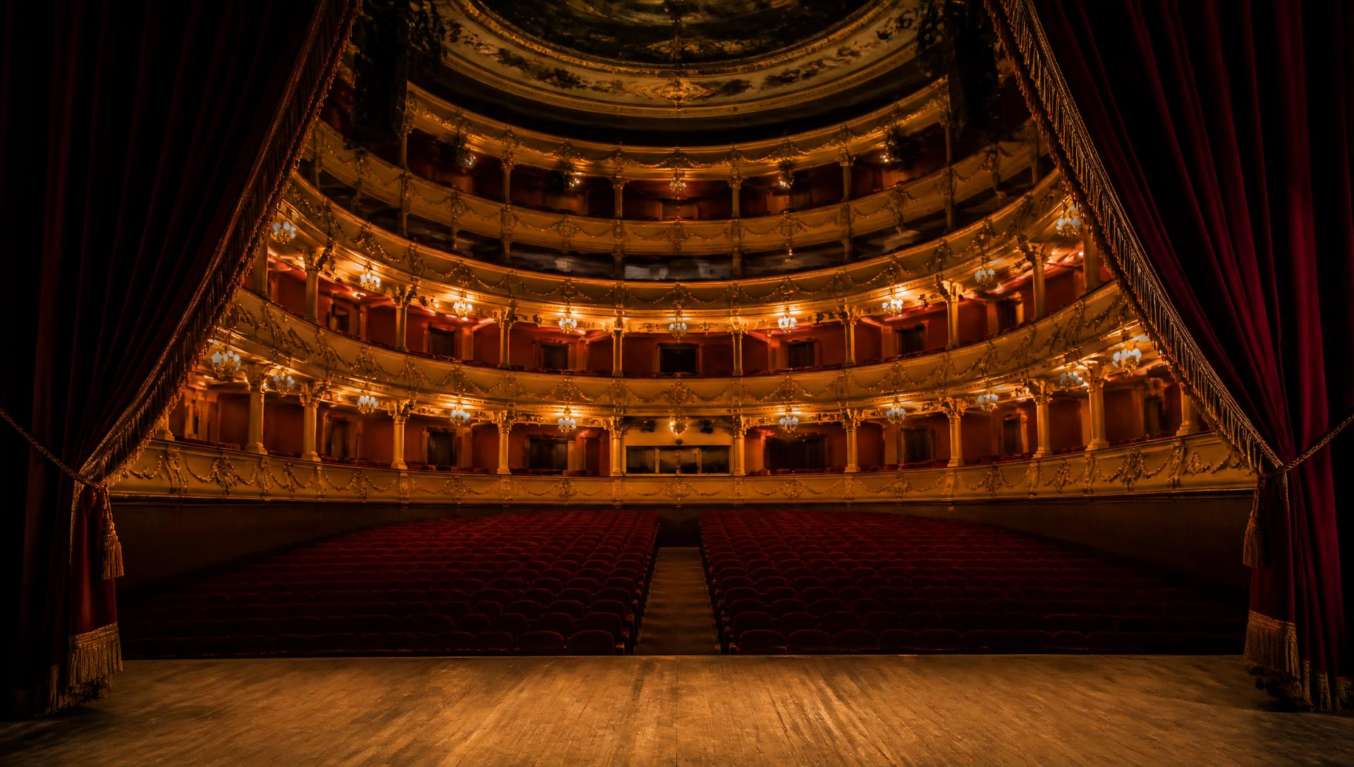 View from the stage of a grand theatre auditorium with red velvet curtains